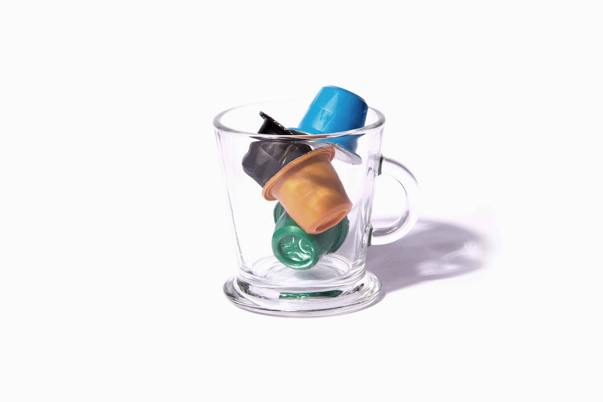 nespresso capsules in an empty clear glass mug