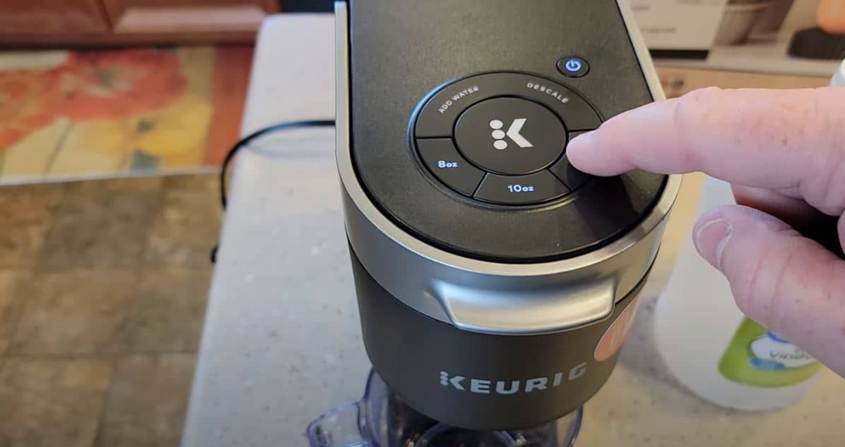 finger pushing 12 oz button on keurig slim